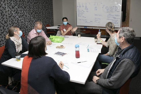 A group of workshop participants sitting around a table discussing simulation scenario design